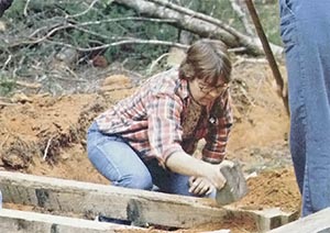 A member tamps dirt around a bridge beam.